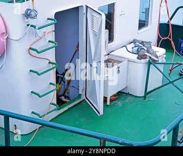 Schiffsdeck mit Blick auf einen Technikraum und aufgerollte Fischernetze eines Garnelenfischschiffs in den Farben weiß und grün. Deutschland, Ostfriesland. Stockfoto