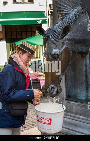 Belgien, Flandern, Brügge, Wijngaardstraat, Kutschenfahrer füllen Eimer an der Springbrunne des Pferdekopfes Stockfoto