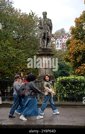 Gruppe junger Frauen, die an einem bewölkten Tag im frühen Herbst an der Statue von Allan Ramsay in der Princes Street, Edinburgh, Schottland, Großbritannien, vorbeispazieren. Stockfoto