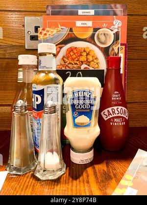 Menüs, Flaschen mit Soße, Salz und Pfeffer auf einem Tisch in einem Restaurant Stockfoto