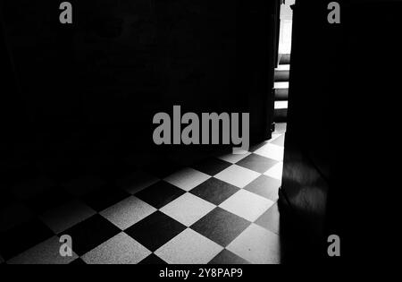 Abstrakter Schwarzweiß-Hintergrund. Eingang in einen Raum mit schwarz-weißen Quadraten auf dem Boden. Stockfoto