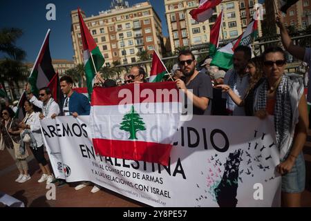 Malaga, Spanien. Oktober 2024. Während einer globalen Demonstration gegen den Völkermord in Palästina nach der Eskalation des Nahost-Konflikts halten die Demonstranten ein großes Banner und eine libanesische Flagge. Einen Tag vor dem Jahrestag der Anschläge vom 7. Oktober und dem Beginn des Krieges zwischen Israel und Hamas gehen Tausende von Menschen in Solidarität mit dem Libanon und Palästina auf die Straßen der Stadt Malaga, um ein Ende des Waffenhandels mit Israel und der israelischen militärischen Besatzung in Palästina zu fordern. Quelle: SOPA Images Limited/Alamy Live News Stockfoto