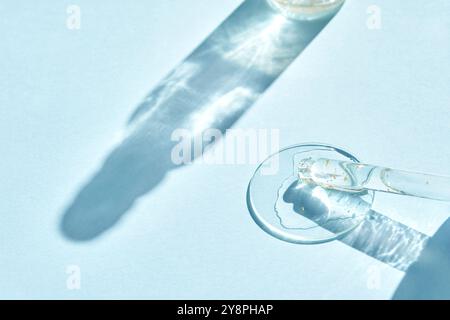 Farbfeld mit Serum-Gel-Textur. Transparenter Tropfen mit goldenen Funkeln. Blauer Hintergrund. Gesichtspflegeprodukt. Essenz aus flüssigem Öl. Beauty Collagen Splash. Organische Peeling-Behandlung. Körperpflege Stockfoto