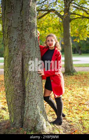 Nachdenkliche junge Frau mit Brille steht an einem Baum im herbstlichen Park *** nachdenkliche junge Frau mit Brille steht an einem Baum in einem herbstlichen Park Stockfoto