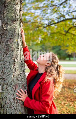 Nachdenkliche junge Frau mit Brille steht an einem Baum im herbstlichen Park *** nachdenkliche junge Frau mit Brille steht an einem Baum in einem herbstlichen Park Stockfoto