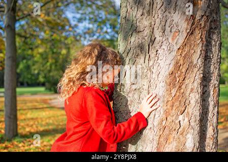 Nachdenkliche junge Frau mit Brille steht an einem Baum im herbstlichen Park *** nachdenkliche junge Frau mit Brille steht an einem Baum in einem herbstlichen Park Stockfoto