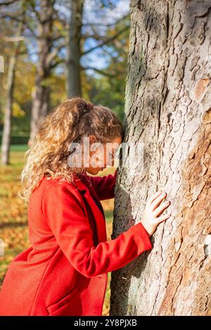 Nachdenkliche junge Frau mit Brille steht an einem Baum im herbstlichen Park *** nachdenkliche junge Frau mit Brille steht an einem Baum in einem herbstlichen Park Stockfoto