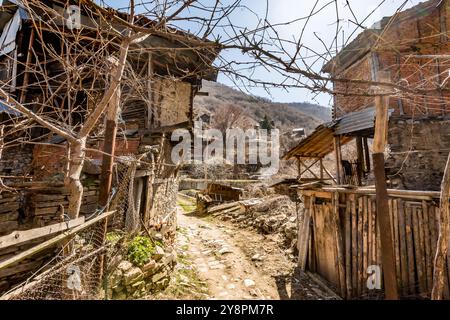 Verlassene Häuser und andere Gebäude, beleuchtet durch Sonnenlicht, Blick auf die Straße, Pirin Dorf und Berg, Bulgarien Stockfoto