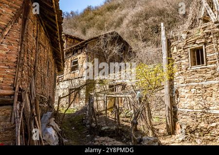 Verlassene Häuser und andere Gebäude, beleuchtet durch Sonnenlicht, Blick auf die Straße, Pirin Dorf und Berg, Bulgarien Stockfoto