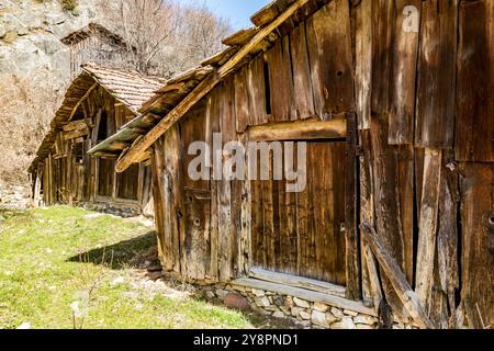 Verlassene Häuser und andere Gebäude, beleuchtet durch Sonnenlicht, Blick auf die Straße, Pirin Dorf und Berg, Bulgarien Stockfoto