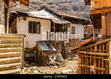 Verlassene Häuser und andere Gebäude, beleuchtet durch Sonnenlicht, Blick auf die Straße, Pirin Dorf und Berg, Bulgarien Stockfoto