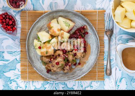 Traditionelle schwedische Fleischbällchen in cremiger Sauce mit gekochten Kartoffeln und Preiselbeeren Stockfoto