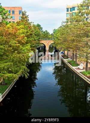 Wasserstraße mit Gehwegsbrücke und Gebäuden im Woodlands TX Stockfoto