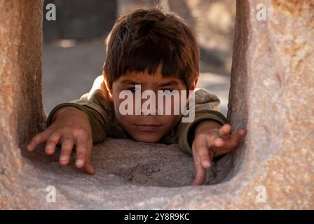 Ein Porträt eines mexikanischen Jungen mit dunklen Haaren, der auf einem Felsen liegt Stockfoto