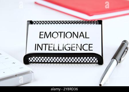 Geschäftskonzept. Der Satz, der Text und die Worte der EMOTIONALEN INTELLIGENZ sind auf einer weißen Visitenkarte in einem Stand auf einer weißen Oberfläche geschrieben. Stockfoto