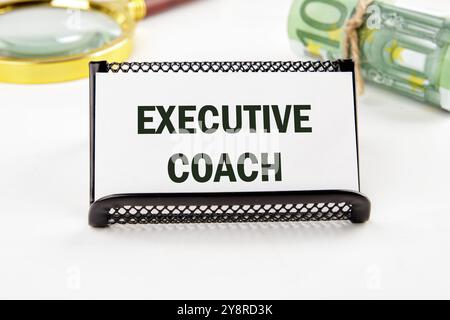 Geschäftskonzept. Der Satz, der Text, das Wort EXECUTIVE COACH stehen auf einer weißen Visitenkarte in einem Stand, der auf einer weißen Oberfläche in Nahaufnahme steht. Stockfoto