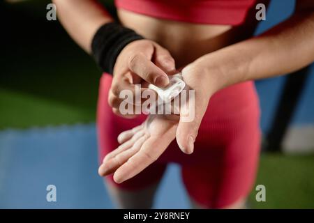Nahaufnahme der Hände einer nicht erkennbaren weiblichen Turnerin, die Kreide in die Handflächen einreiben und Magnesia-Pulver auftragen, um den hohen Griff im Fitnessstudio zu verbessern, und Kopierraum Stockfoto