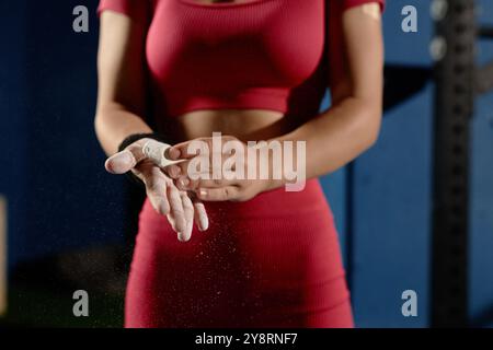 Nahaufnahme der Hände von nicht erkennbaren weiblichen Turnerinnen, die Hände kreiden, um Magnesia in die Handflächen zu reiben, um sicher auf der hohen Bar im Fitnessstudio zu üben, Kopierraum Stockfoto