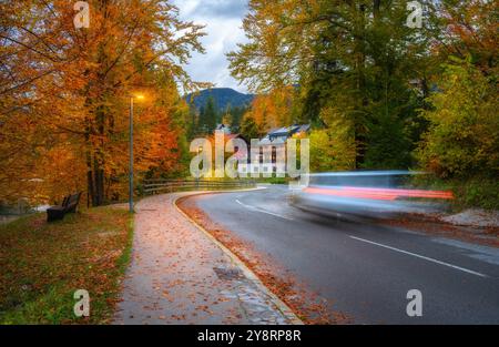 Verschwommenes Auto auf kurvenreicher Straße mit gefallenem Laub im Herbst Stockfoto