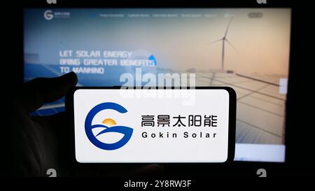 In dieser Fotoabbildung hält eine Person ein Handy mit dem Logo des chinesischen Photovoltaik-Unternehmens Gokin Solar Co. Ltd. Vor der Geschäftswebseite. Stockfoto