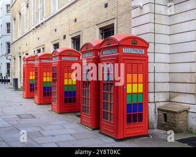 London, Großbritannien - 25. Juni 2024: Eine Reihe traditioneller roter Telefonzellen mit farbenfrohen Glaspaneelen - Gay Pride Event Stockfoto