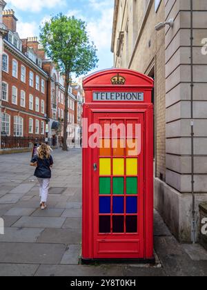 London, Großbritannien - 25. Juni 2024: Eine Reihe traditioneller roter Telefonzellen mit farbenfrohen Glaspaneelen - Gay Pride Event Stockfoto