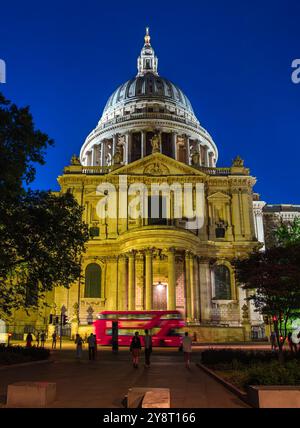 London, Großbritannien - 25. Juni 2024: Ein roter Doppeldeckerbus fährt nachts vor einer beleuchteten St. Pauls Cathedral. Stockfoto