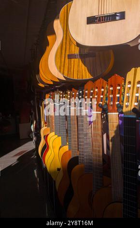 Spanisches Gitarrengeschäft. Sonnenstrahlen beleuchten teilweise die Gitarren Stockfoto