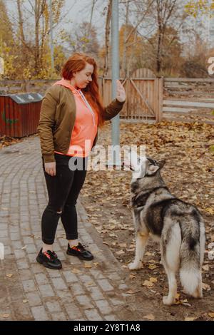 Das Mädchen gibt Befehle für Fluchen. Der Prozess der Integration des Einzelnen in das soziale System. Eine Frau geht mit einem Husky im Park spazieren. Stockfoto
