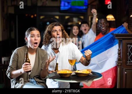 Ein Paar jubelte in der Sportbar vor dem Hintergrund von Fans mit der Flagge von Serbien und Montenegro Stockfoto