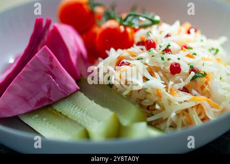 Sauerkraut mit Preiselbeeren, Tomaten und eingelegtem Gemüse, serviert auf einem weißen Teller Stockfoto