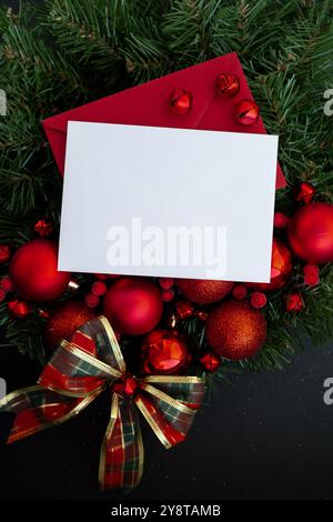 Grußkarte mit Kopierraum weißes Papierblatt auf handgemachtem Weihnachtskranz. Festliche Stimmung Neujahrsfeier. Postkartendekoration, Draufsicht, flach gelegen Stockfoto