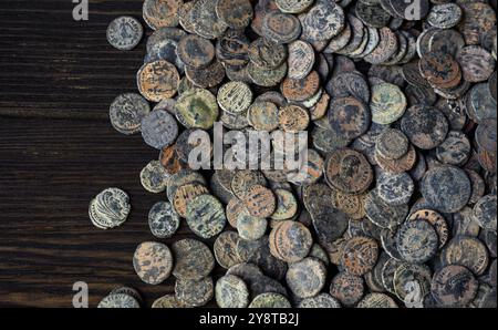 Stapel von römischen Bronzemünzen auf einem alten dunklen Holztisch, Blick von oben auf das antike Geld, Vintage Hintergrund. Das Konzept der Antike, des Imperiums, der Textur, der Zivilisation Stockfoto