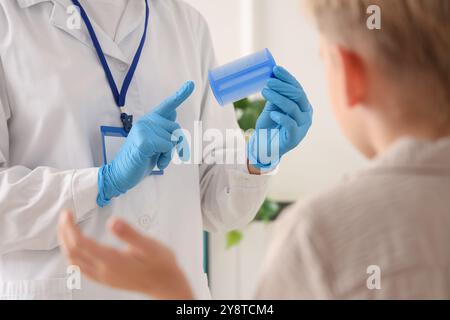 Ärztin mit Kopfläuse-Kamm und kleiner Junge mit Pedikulose in der Klinik, Nahaufnahme Stockfoto