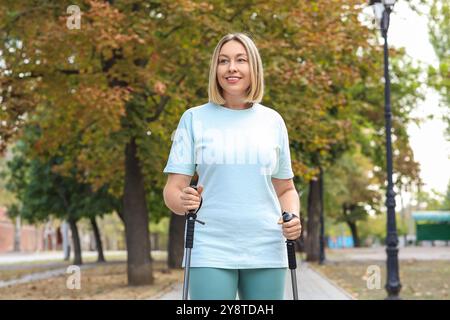 Sportliche Frau beim Nordic Walking auf der Straße Stockfoto