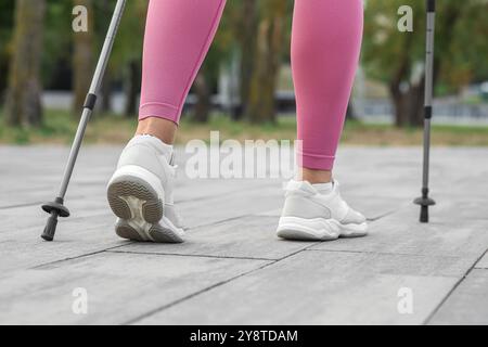 Sportliche Frau, die Nordic Walking auf der Straße macht, Rückansicht Stockfoto