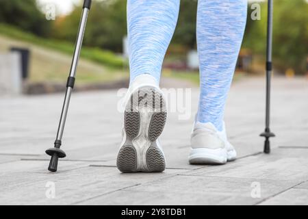 Sportliche Frau, die Nordic Walking auf der Straße macht, Rückansicht Stockfoto