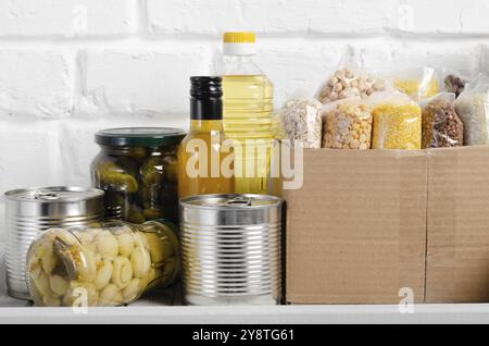 Set von ungekochten Lebensmitteln auf Speisekammer Regal für Katastrophen Notsituationen auf Backstein Wand Hintergrund Nahaufnahme vorbereitet Stockfoto