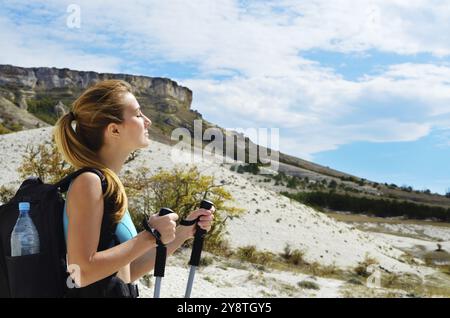 Junge Frau mit Rucksack und Wanderstöcken in den Bergen Stockfoto