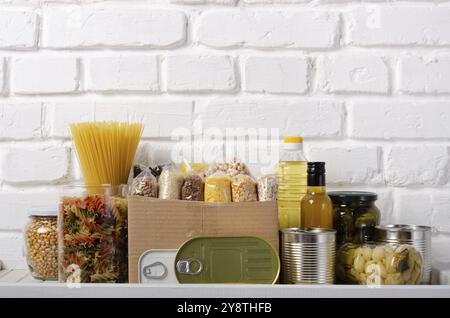 Ein Satz ungekochte Lebensmittel auf einem Regal für Vorratsraum, vorbereitet für Notfälle auf Backsteinwand Stockfoto