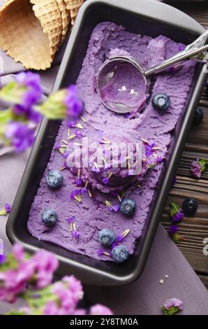 Flache Sicht auf Brombeereis in Metalltablett serviert mit Blütenknospen und Brombeeren auf Küchentisch Stockfoto