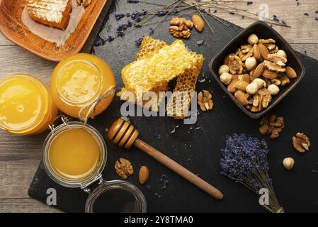 Wabenplatte auf Schieferplatte mit Honig und Nüssen auf Küchentisch Stockfoto