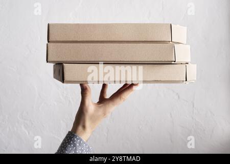 Kaukasische männliche Hände halten drei Pizzaschachteln mit Seitenansicht und Kopierraum Stockfoto