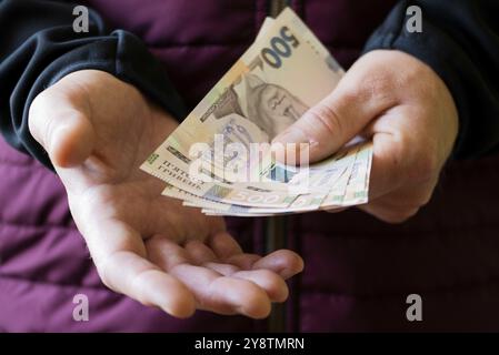 Weißer Mann zeigt ukrainische Griwna-Scheine in seiner Hand in Nahaufnahme Vorderansicht Stockfoto