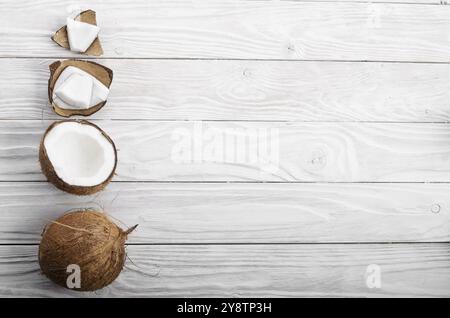 Flach Hintergrund der Kokosnuss, Kokosnussschalen und Fleischstücke auf weissem Holztisch Stockfoto