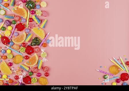 Flach auf Süße Hintergrund unterschiedlicher Art Farbe und Geschmack Bonbons und Geburtstag Kerzen auf Rosa. Platz für Text Stockfoto