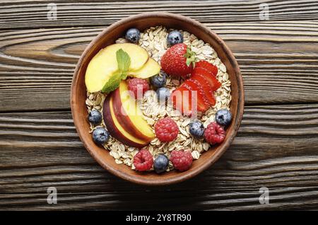 Flach von Obst gesund Müsli mit Pfirsich Erdbeere Mandeln und Black in Ton Teller auf hölzernen Küchentisch Stockfoto