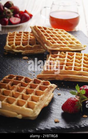 Hausgemachte belgische Waffeln auf Schiefer Tablett mit Ahornsirup und Erdbeeren beiseite Stockfoto