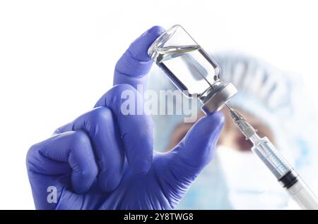 Kaukasische Ärztin in Schutzhandschuhen und Maske füllen Spritze mit Medizin für die Injektion Stockfoto
