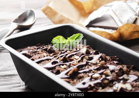 Schokoladeneis in Metallschale mit Minzblatt und Mandelnüssen Stockfoto
